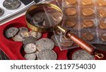 Numismatics. Old collectible coins made of silver on a wooden table.Coins in the album.Collection of old coins. Magnifying glass