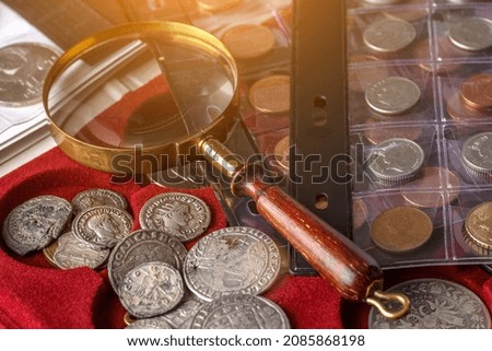 Numismatics. Old collectible coins made of silver on a wooden table.Coins in the album.Collection of old coins. Magnifying glass