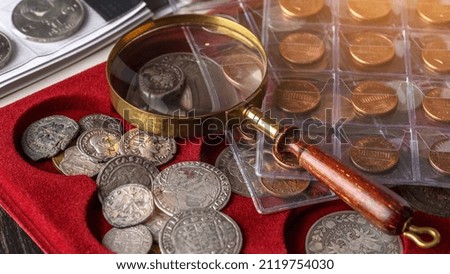 Numismatics. Old collectible coins made of silver on a wooden table.Coins in the album.Collection of old coins. Magnifying glass