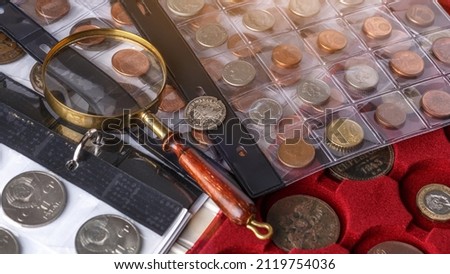 Numismatics. Old collectible coins made of silver on a wooden table.Coins in the album.Collection of old coins. Magnifying glass
