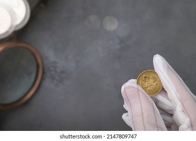 Numismatics. Old Collectible Coins Of Silver, Gold And Copper On The Table.  A Collector In Special Gloves Holds An Old Coin. Top View.