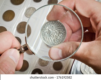 The Numismatist Examines A Coin From The Collection