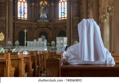 The nun sits in the church and prays to God. A nun in traditional white robes meditates in a Christian cathedral. Prayer to Jesus.