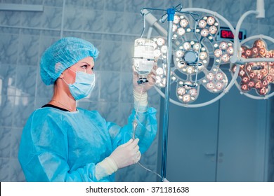 Nurse adjusting infusion bottle with against background of the o - Powered by Shutterstock