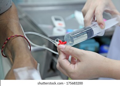 Nurse Adjusting Infusion Bottle With Patient Lying On Bed In Hospital 