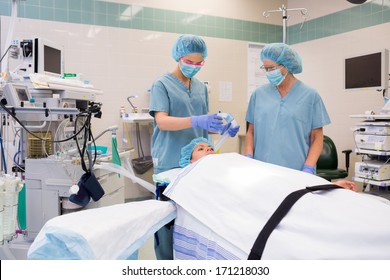 Nurse adjusting oxygen mask on patient while colleague standing by in operation room - Powered by Shutterstock