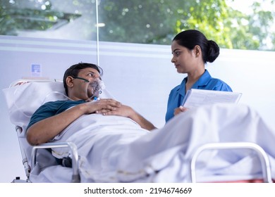 Nurse adjusting a positive pressure oxygen mask on a woman patient lying in bed on a hospital - Powered by Shutterstock