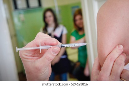 Nurse Administering Vaccination To Students Arms In A High School.