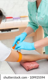 A Nurse Applies A Tourniquet On A Patients Arm Before Blood Drawing