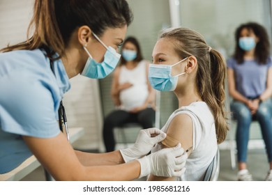 A nurse applying a adhesive patch to a cute teenager girl after receiving the Covid-19 vaccine.