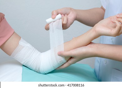 Nurse Applying Bandage To Patient Injured Elbow