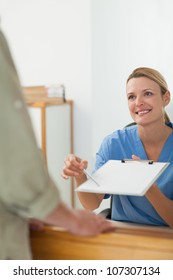 Nurse Asking The Signature Of A Patient At A Hospital Reception, Healthcare Workers In The Coronavirus Covid19 Pandemic