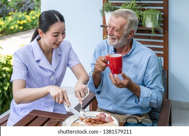 Nurse assist elderly senior man to eat breakfast and drink coffee with mug in hand at nursing home - Powered by Shutterstock