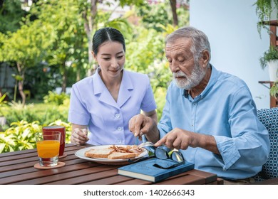 Nurse assist elderly senior man to eat breakfast at nursing home - Powered by Shutterstock