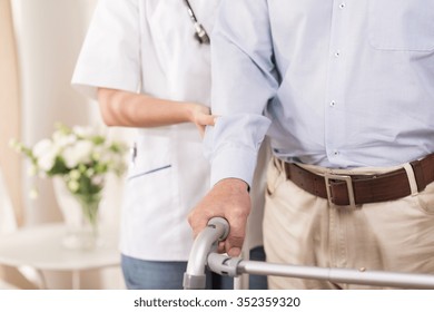 Nurse Assisting An Elderly Man With A Walking Frame