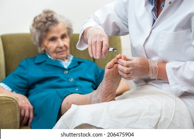 Nurse assists an elderly woman with chiropody and body care at home