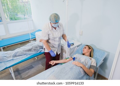 Nurse attaching intravenous tube to patient's hand in hospital bed - Shutterstock ID 1059916133