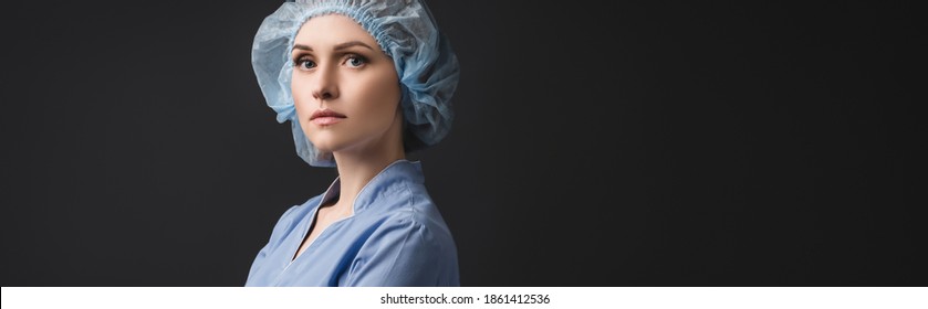 Nurse In Blue Medical Cap Looking At Camera Isolated On Dark Grey, Banner