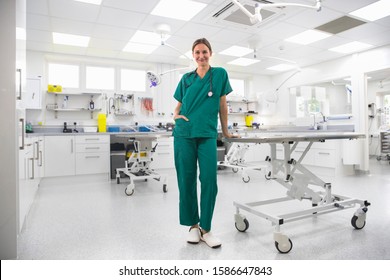 Nurse By Table In Examination Room Of Vet Surgery Smiling At Camera