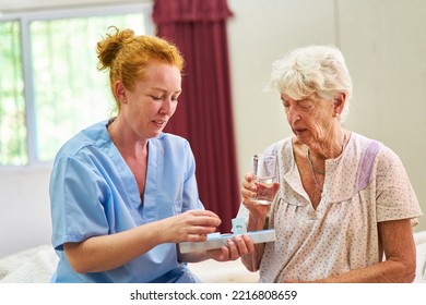 Nurse Or Caregiver Giving Medication To Senior Woman In Nursing Home Or Hospital