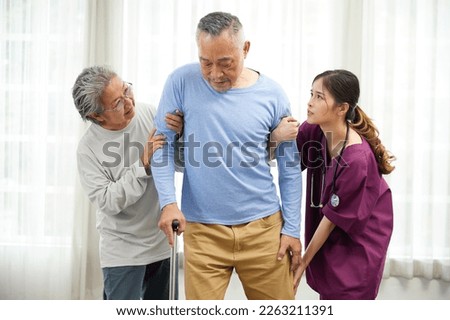 nurse or caregiver and senior woman helping senior man patient with walking stick at home