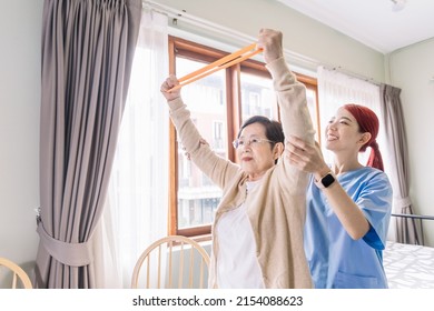 Nurse caregiver wearing scrubs exercises with a senior Asian woman by using resistance band exercise for the senior patient in physiotherapy treatment. Home health care and nursing home concept. - Powered by Shutterstock