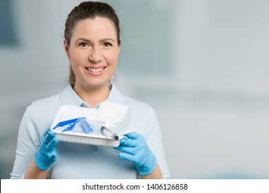 A nurse with a catheter set in front of a clinic room