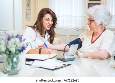 Nurse with clipboard writing results of blood pressure measurement of female senior patient.