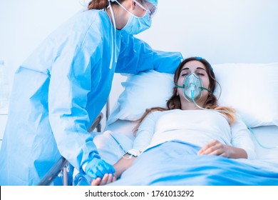 Nurse Comforting A Sick Patient Wearing A Mask For Positive Pressure Oxygen For Respiratory Diseases During The Covid-19 Pandemic In The Ward As She Lies In Bed