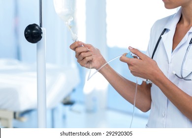 Nurse connecting an intravenous drip in hospital room - Powered by Shutterstock