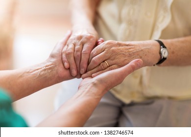 Nurse consoling her elderly patient by holding her hands