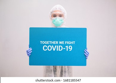 Nurse With Disposable Coverall And Mask Wearing Safety Glasses Holding A Sign Covid-19. Pandemic 2019 Coronavirus 2019-nCoV.