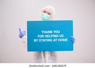 Nurse With Disposable Coverall And Mask Wearing Safety Glasses Holding A Sign Stay At Home. Pandemic 2019 Coronavirus 2019-nCoV.