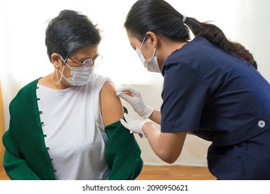 Nurse Or Doctor Giving Shot To Senior Female Patient. Retired Woman In Medical Face Mask Getting Flu Or Covid-19 Vaccine Injection In Her Arm.