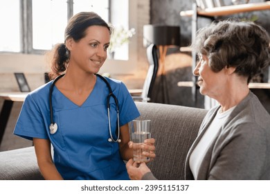 Nurse doctor medical staff giving a glass of water to take medications pills drugs for treatment recuperation. Hospice, private clinic. Taking care of lonely seniors - Shutterstock ID 2395115137