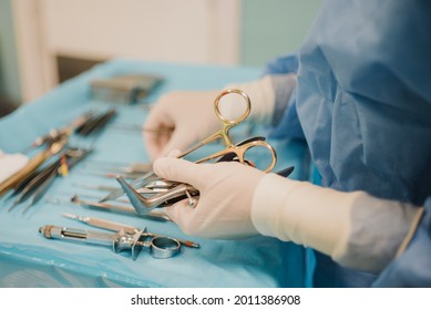 Nurse Doctor Preparing Surgical Equipment For Operation Inside Emergency Hospital Room - Focus On Hand Holding Scissors