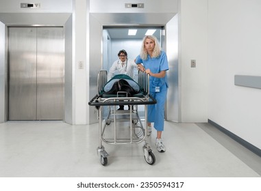 A nurse and doctor in propels a wheeled stretcher, carrying a patient out of the elevator to the emergency room of the hospital. - Powered by Shutterstock