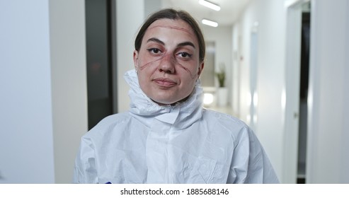 Nurse or doctor in protective clothing with her goggles and face mask removed looking at camera in hospital before turning to walk away during the Covid-19 coronavirus pandemic. - Powered by Shutterstock