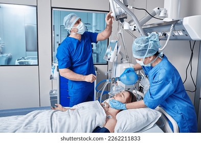 Nurse and doctor using medical ventilator on female patient while cardiopulmonary resuscitation in ICU and monitoring health. CPR in ICU - Powered by Shutterstock