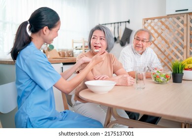 Nurse Or Doctor Who Work As Homecare Staff Help To Serve A Spoon Of Mush Rice To Senior Woman With Her Husband Sit Beside.