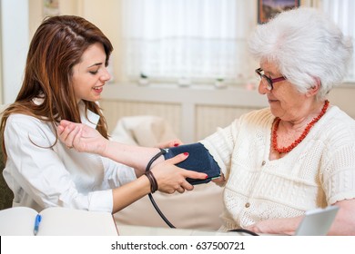 Nurse Doing Blood Pressure Monitoring For Senior Woman At Home.