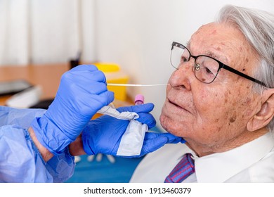 Nurse Dressed In Coronavirus Protective Suit And Mask, Performing Coronavirus Test On Elderly Man.