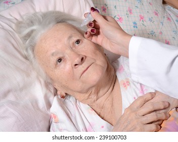 Nurse dripping eye drops to old woman in the hospital