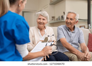 Nurse during home visit with senior couple. Doctor holding clipboard and stethoscope in conversation with old couple at home. Nurse bringing home the results of medical exams.