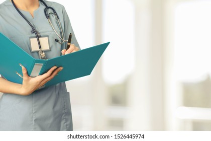 A Nurse Enrolled In A Bachelor Of Science In Nursing Degree Program, Holding A Binder In Her Arms And Wearing A Stethoscope.