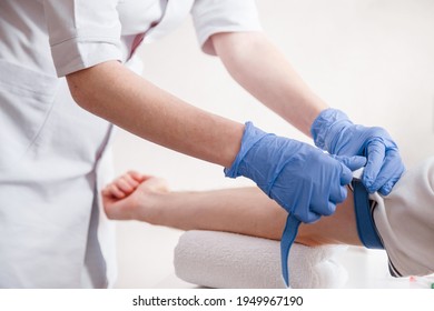 Nurse fastens the medical tourniquet on arm before taking blood test.