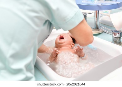 A Nurse Gives The First Bath Of A Newborn Baby