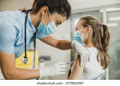 Nurse giving the Covid-19 vaccine to a cute teenager girl due to pandemic. - Shutterstock ID 1979852987