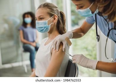 Nurse Giving The Covid-19 Vaccine To A Cute Teenager Girl Due To Pandemic.