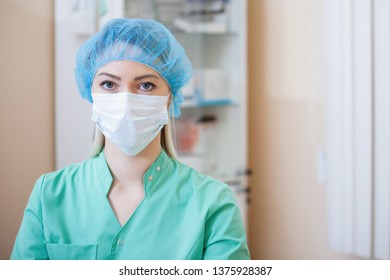 Nurse in green uniform in a cap, mask, in a medical office posing on camera. - Shutterstock ID 1375928387